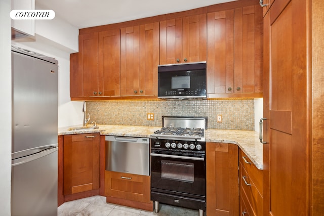 kitchen with a sink, black appliances, brown cabinetry, and backsplash