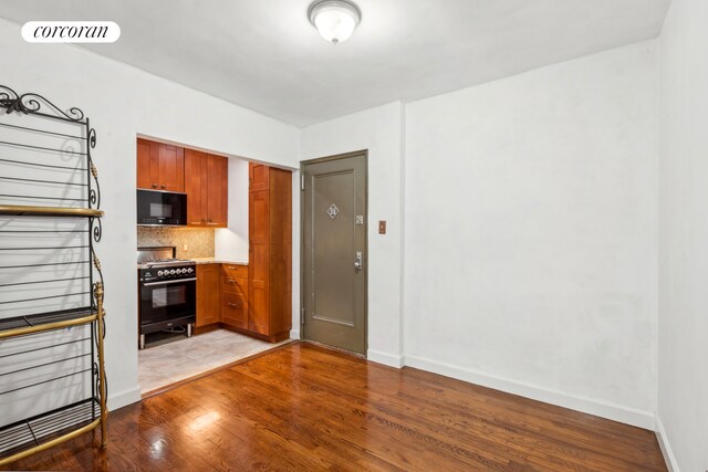 kitchen featuring light hardwood / wood-style flooring, decorative backsplash, and black appliances