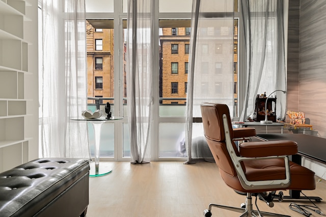 interior space with a wall of windows, a wealth of natural light, and wood finished floors