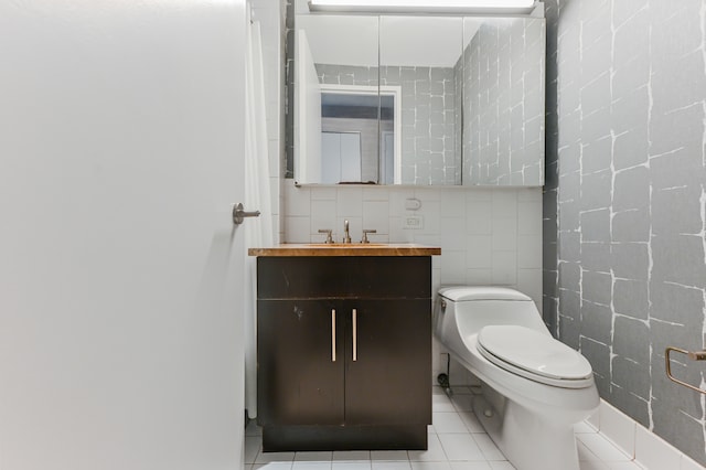 bathroom with toilet, tile patterned flooring, vanity, and tile walls