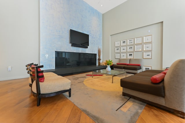 living area with a fireplace, a high ceiling, and wood finished floors