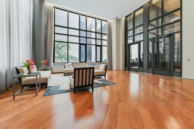 interior space with light wood-type flooring, a high ceiling, and expansive windows