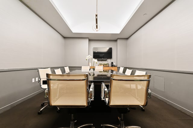 office area with a tray ceiling, a decorative wall, and baseboards