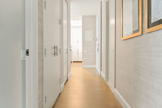 hall featuring light wood-style flooring and baseboards