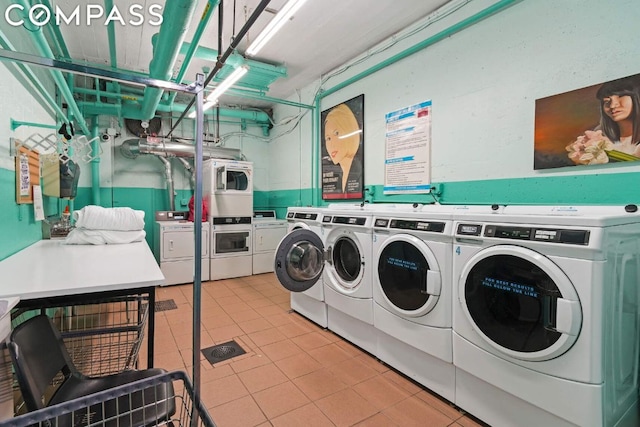 laundry room with light tile patterned floors, stacked washer and clothes dryer, and washing machine and clothes dryer