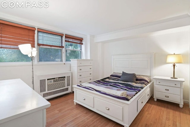 bedroom with light hardwood / wood-style flooring, ornamental molding, and a wall mounted AC