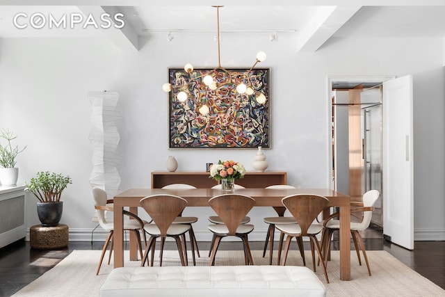 dining room featuring beam ceiling, a notable chandelier, wood finished floors, and track lighting