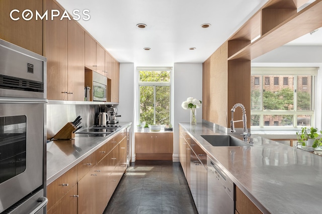 kitchen featuring modern cabinets, a sink, stainless steel countertops, tasteful backsplash, and appliances with stainless steel finishes