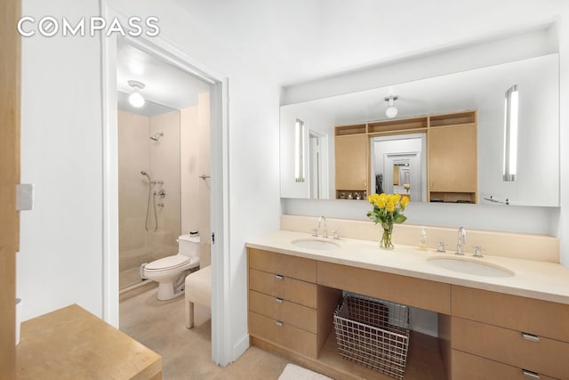 bathroom with a tile shower, double vanity, toilet, and a sink