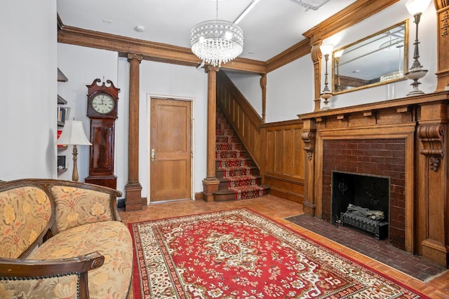 living room featuring ornamental molding, a fireplace, a chandelier, and decorative columns