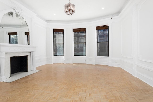 unfurnished living room featuring a fireplace, a chandelier, and light parquet floors