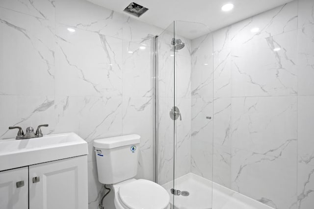 bathroom with vanity, a tile shower, tile walls, and toilet