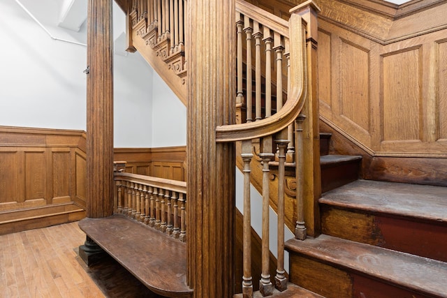 staircase featuring a wainscoted wall and wood finished floors