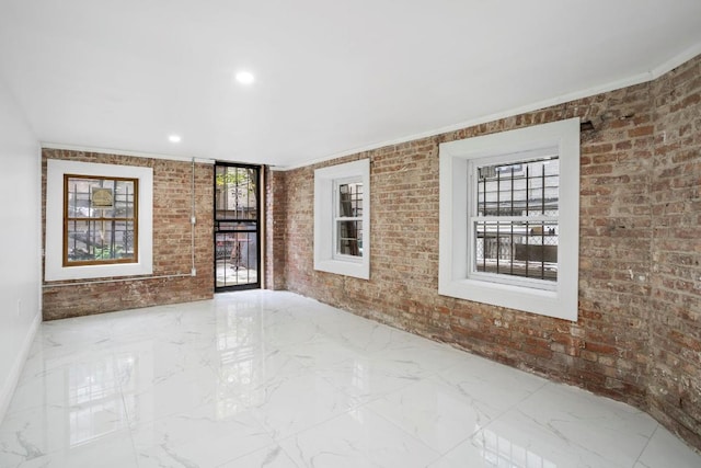 interior space featuring a wealth of natural light, ornamental molding, and brick wall