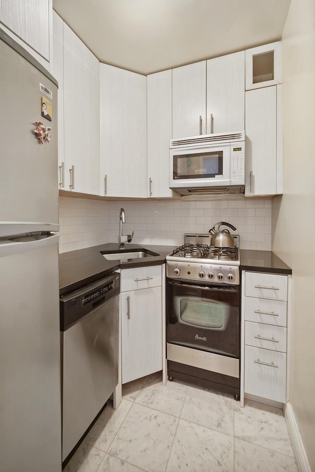 kitchen with dark countertops, tasteful backsplash, appliances with stainless steel finishes, and a sink