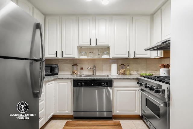 kitchen with stainless steel appliances, backsplash, white cabinets, a sink, and under cabinet range hood