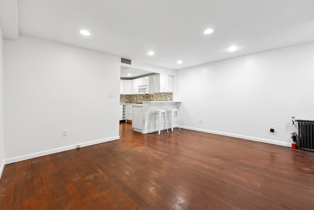 473 W 140th St, New York City, NY 10031 - unfurnished living room featuring dark wood-style flooring, radiator heating unit, and recessed lighting