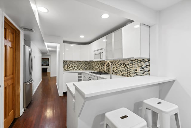 473 W 140th St, New York City, NY 10031 - kitchen with freestanding refrigerator, white microwave, a peninsula, modern cabinets, and dark wood finished floors