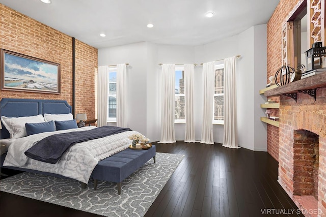 bedroom featuring a brick fireplace, dark hardwood / wood-style floors, and brick wall