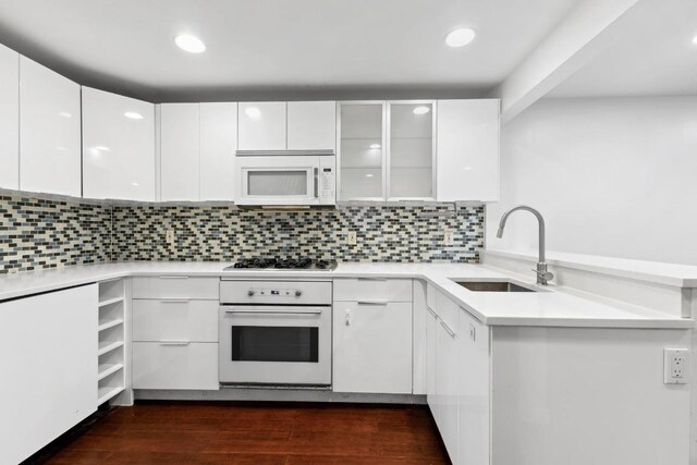 kitchen with white cabinetry, sink, white appliances, dark wood-type flooring, and decorative backsplash