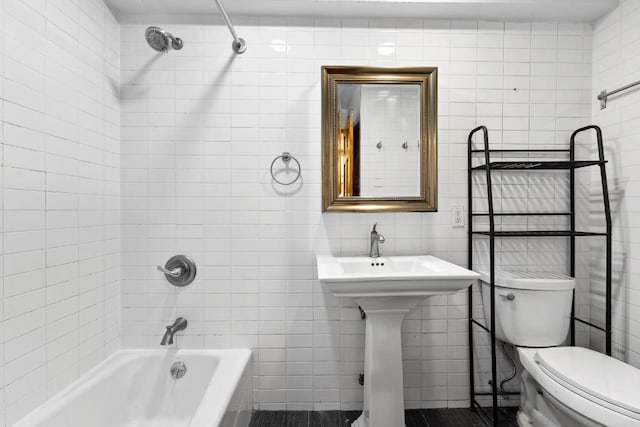 bathroom with tile walls, tiled shower / bath combo, and toilet