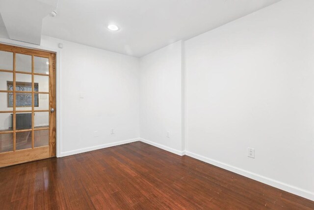 unfurnished room featuring radiator heating unit and dark hardwood / wood-style flooring