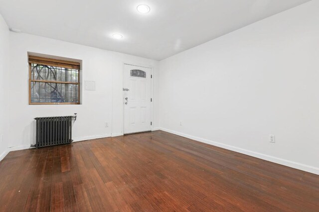 spare room featuring radiator and dark hardwood / wood-style flooring