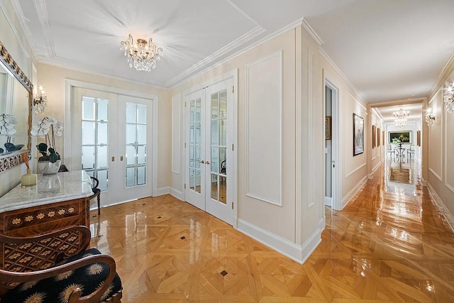 doorway to outside featuring french doors, light parquet flooring, crown molding, and a notable chandelier