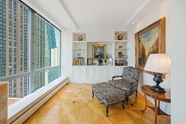 sitting room with built in features, a baseboard heating unit, and a city view