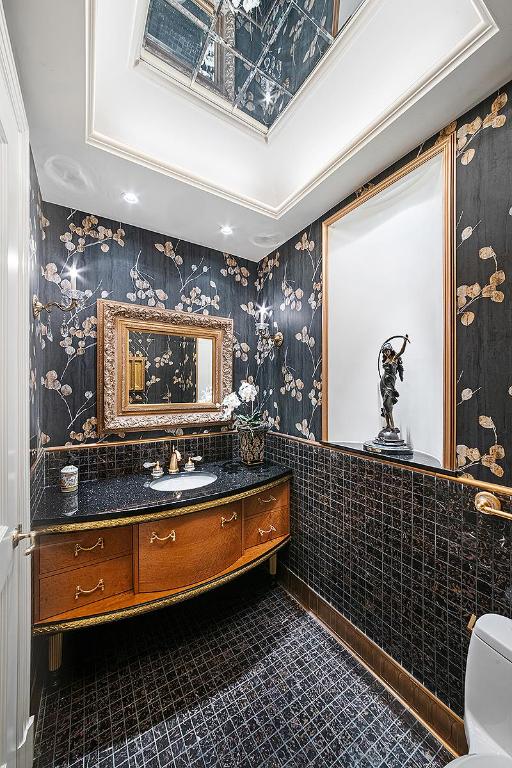 bathroom featuring tile walls, wainscoting, vanity, tile patterned flooring, and wallpapered walls