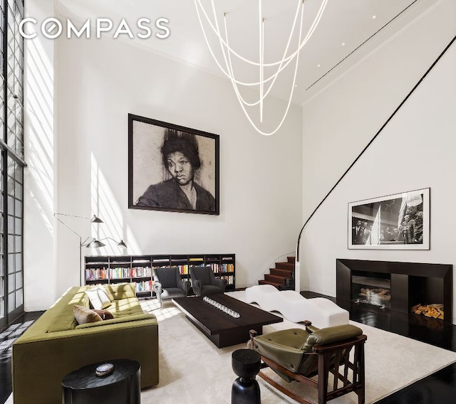 living area featuring ornamental molding, a glass covered fireplace, and a high ceiling