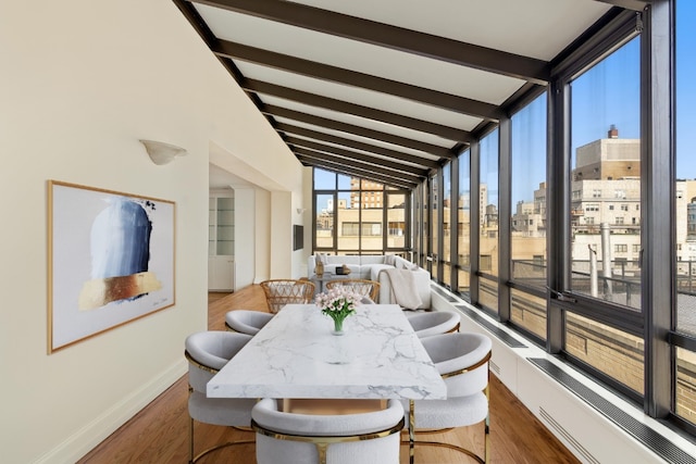 sunroom / solarium featuring vaulted ceiling with beams and a city view