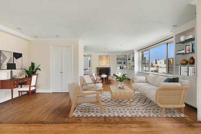 living area with a warm lit fireplace, ornamental molding, wood finished floors, and baseboards