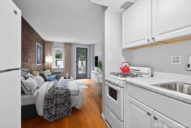 kitchen with white cabinetry, light hardwood / wood-style floors, white appliances, and sink