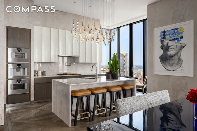 kitchen with tasteful backsplash, a breakfast bar, stovetop, modern cabinets, and a sink