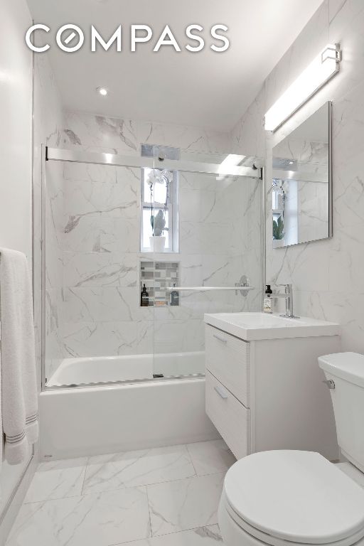 full bathroom featuring vanity, shower / bath combination with glass door, and toilet