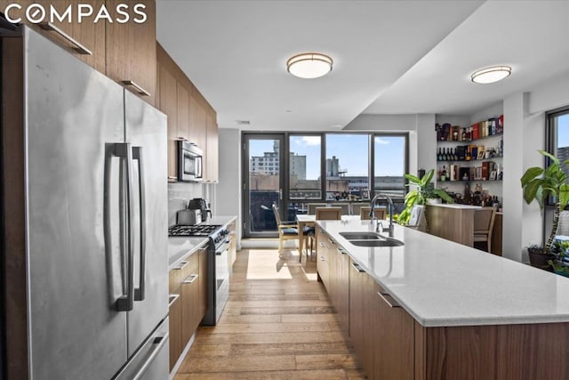 kitchen with a kitchen island with sink, sink, stainless steel appliances, and light hardwood / wood-style floors