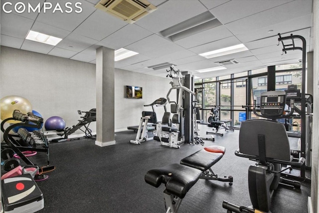 gym with floor to ceiling windows and a drop ceiling