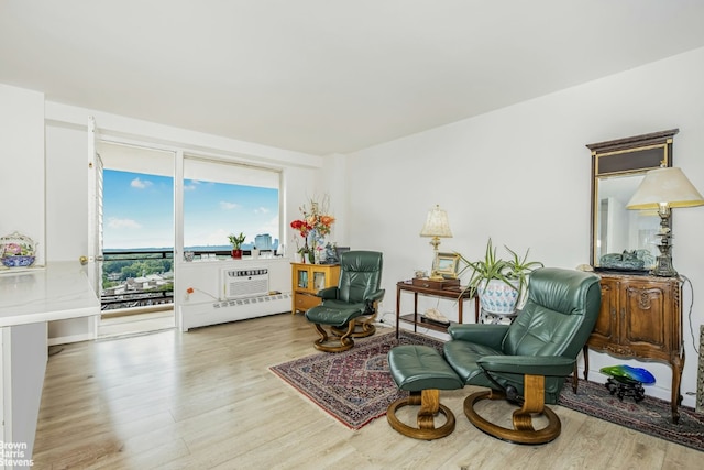 sitting room with an AC wall unit and light wood-type flooring