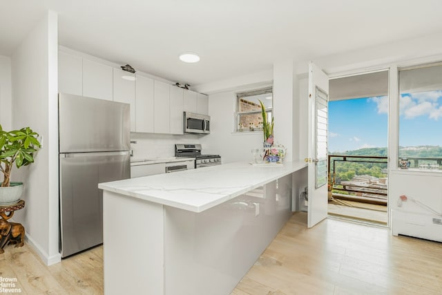 kitchen with appliances with stainless steel finishes, tasteful backsplash, white cabinets, a kitchen bar, and kitchen peninsula