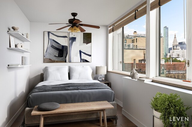 bedroom featuring baseboards, wood finished floors, and a view of city