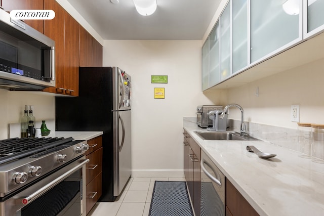 kitchen featuring light tile patterned floors, brown cabinetry, appliances with stainless steel finishes, and a sink