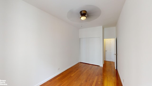 unfurnished bedroom featuring ceiling fan, a closet, and hardwood / wood-style flooring