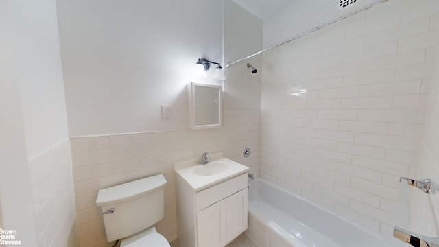 full bathroom with toilet, tile walls, tiled shower / bath, and vanity