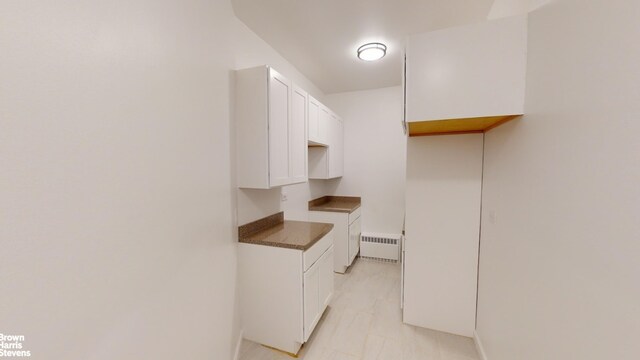 kitchen with radiator and white cabinetry