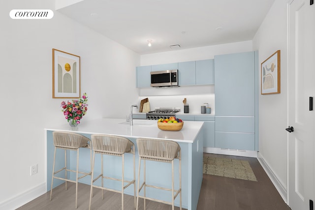 kitchen featuring stainless steel microwave, a sink, visible vents, and a kitchen breakfast bar