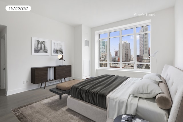 bedroom featuring a view of city, visible vents, baseboards, and wood finished floors