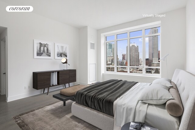 bedroom featuring baseboards, visible vents, a city view, and wood finished floors