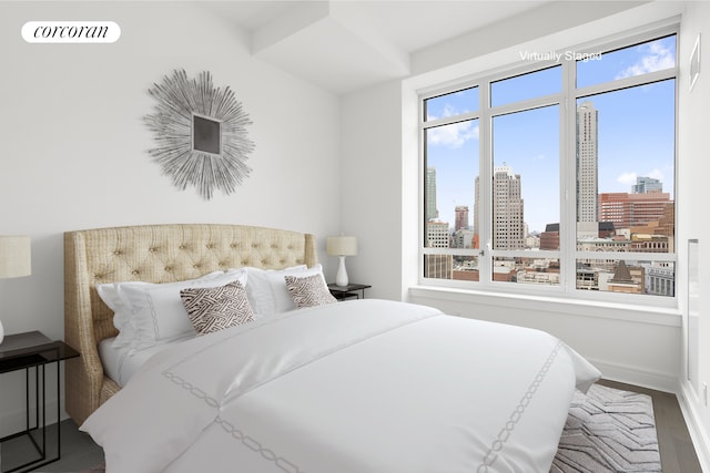 bedroom featuring visible vents, a view of city, baseboards, and wood finished floors