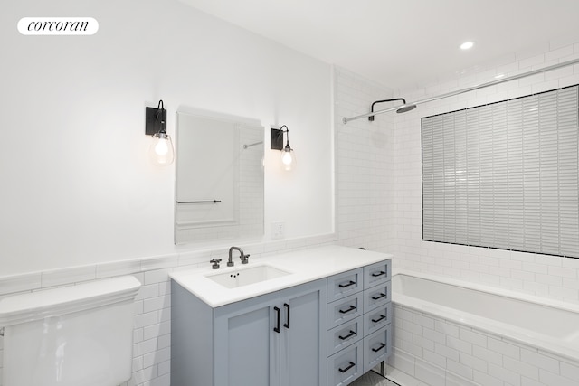 full bath featuring tiled bath, visible vents, toilet, vanity, and tile walls